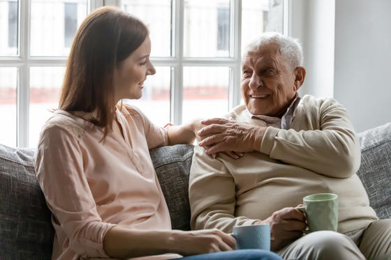 Lächelnde junge Frau genießt Gespräch mit altem Mann